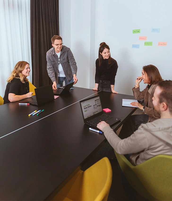 The image shows a group of people sitting around a table, holding a meeting