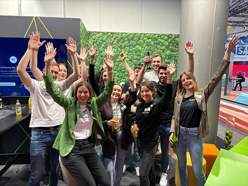 A turquoise and white “fwip” ice cream machine on a counter, with a cup of colorful ice cream beside it and large windows showing buildings in the background.