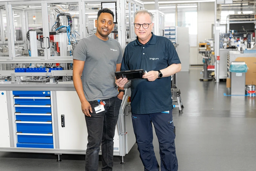 Two INGUN employees standing in a modern production environment, jointly holding a tablet – symbolizing digital collaboration and connected manufacturing processes.