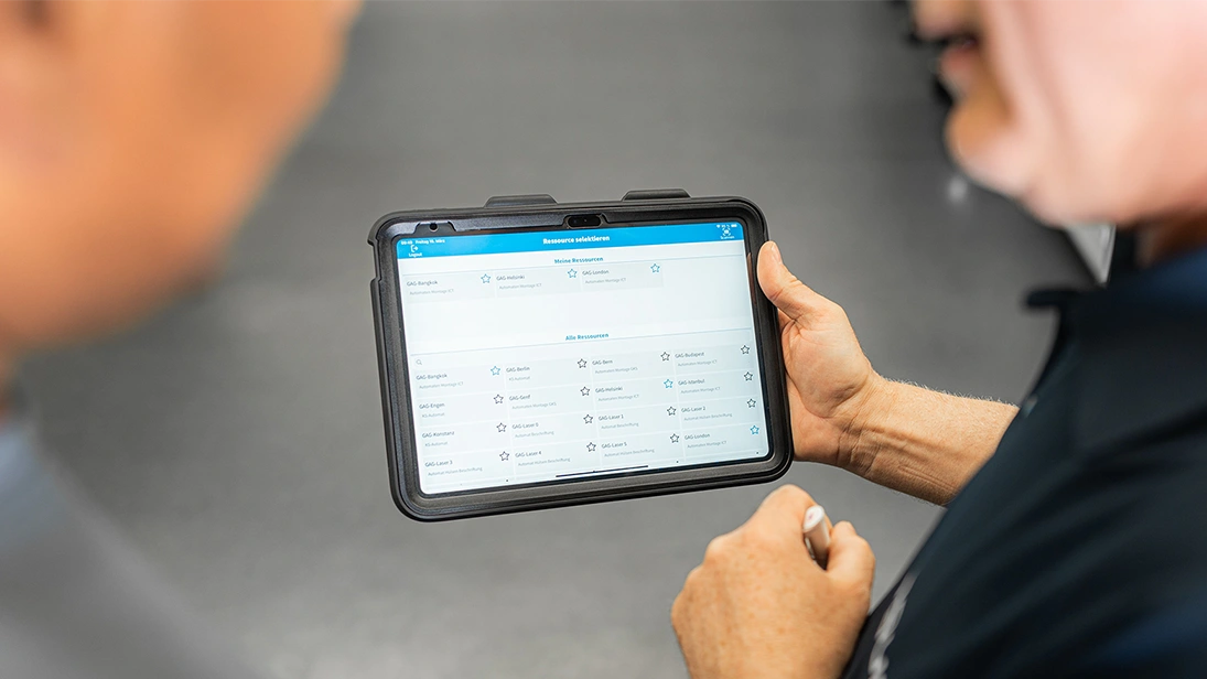Person holding a tablet displaying a production overview – representing digital manufacturing processes and Industry 4.0.