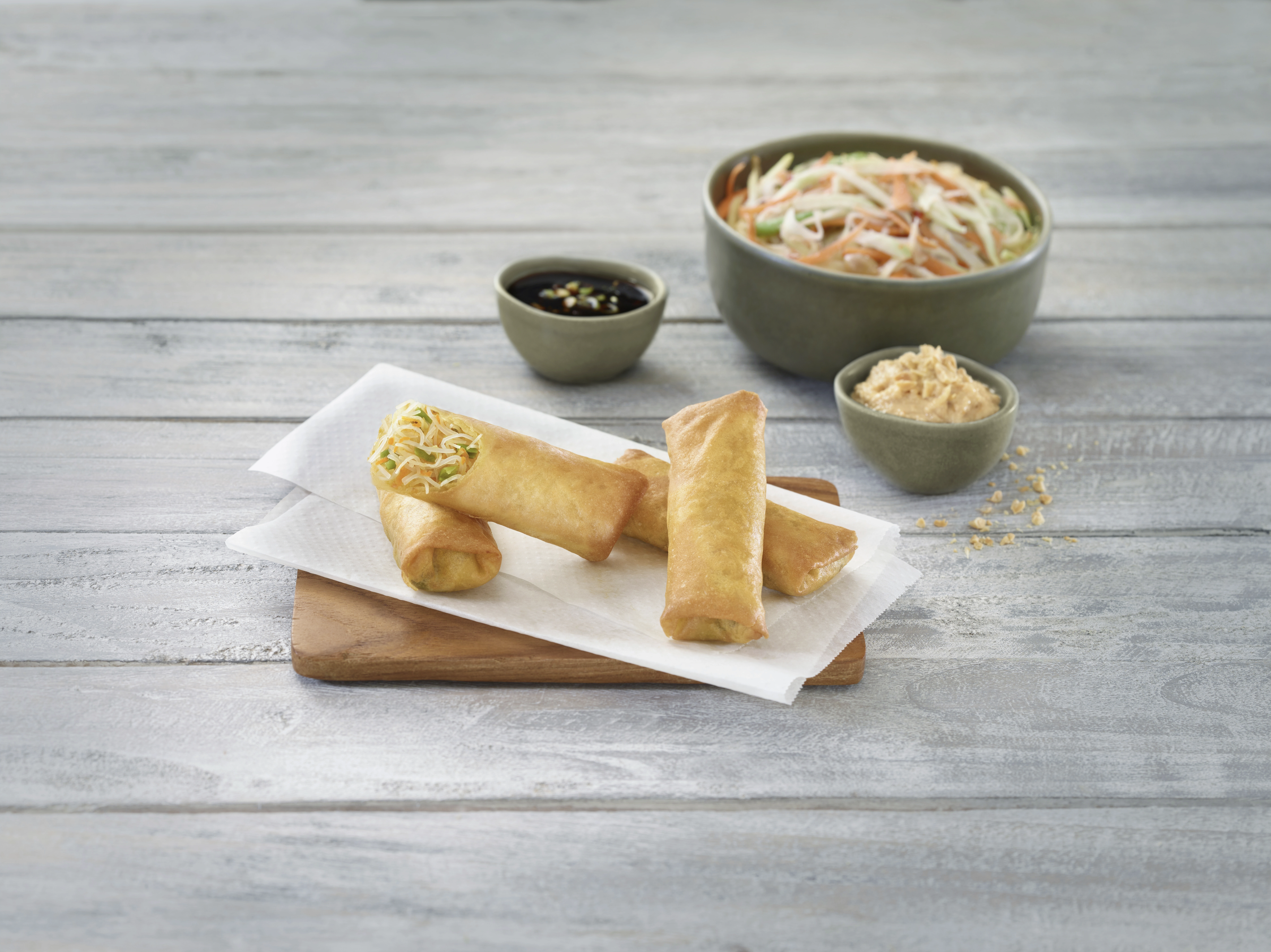 Vegetarische Fr&uuml;hlingsrollen mit knackigem Gem&uuml;se, serviert mit asiatischem Salat, Sojasauce und cremiger Erdnusssauce &ndash; knusprige asiatische Vorspeise.