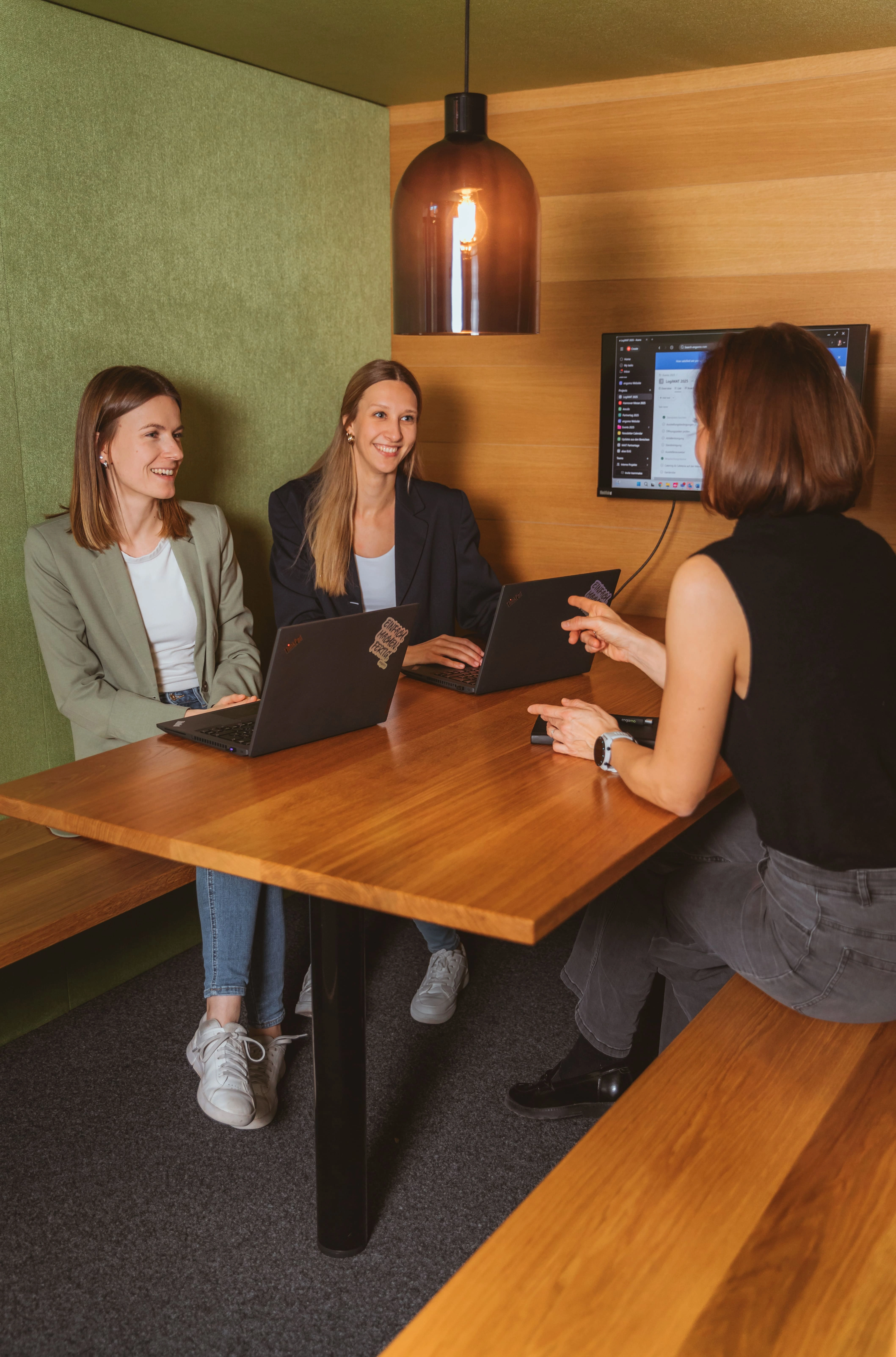 The picture shows two smiling women from the front and one woman from behind during a conversation.