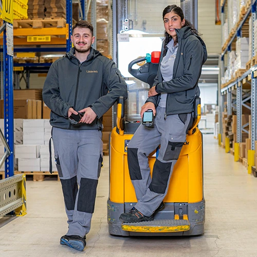 Teaser image for the article showing the warehouse at Läderach, with a forklift that one person is leaning on while another person is sitting on it